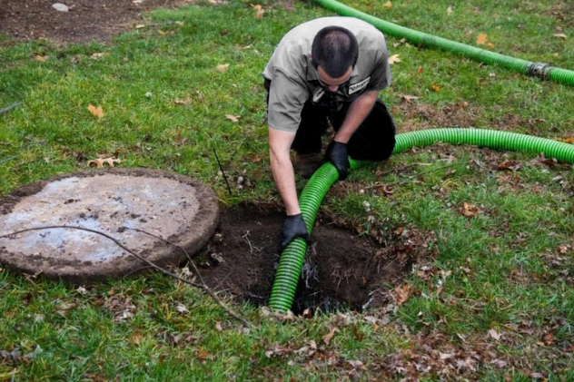 Technician pumping a cesspool system with a vacuum truck for cleaning.