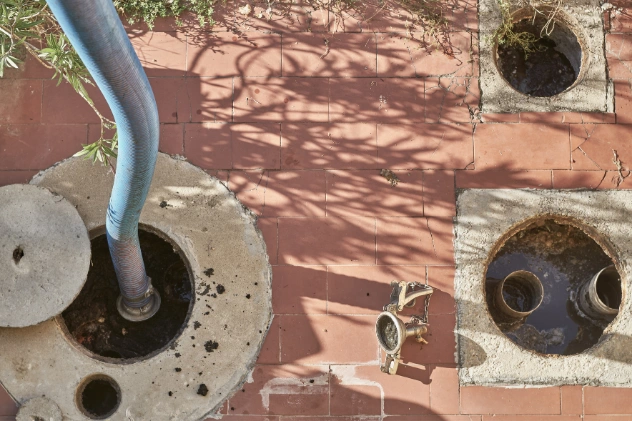 Overhead view of two sewage tanks with hoses inserted for waste pumping.