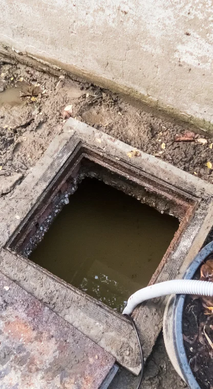 A close-up of a dirty sewage tank with water inside, showing the open lid.