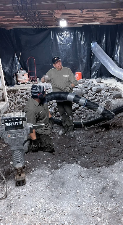 wo workers in protective gear setting up sewage system pipes in a trench,