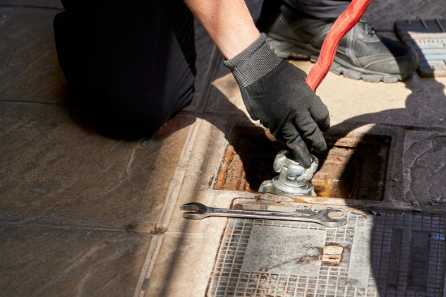 Worker operating vacuum truck to clean street sewer lines