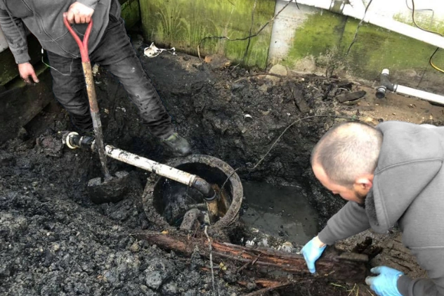 Workers fixing a damaged sewer line using specialized equipment.