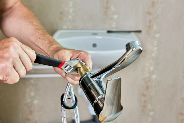Plumber tightening a faucet as part of a home installation project.