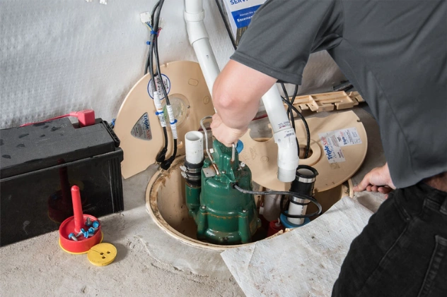 Plumber installing a sump pump in a basement to prevent flooding damage.
