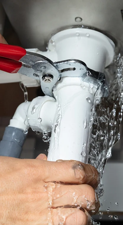 Plumber tightening a pipe with a wrench for plumbing repair.