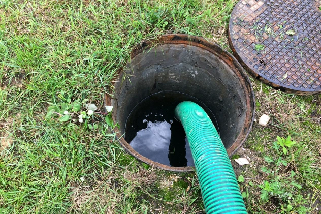 Professional cesspool pumping service with green hose at site