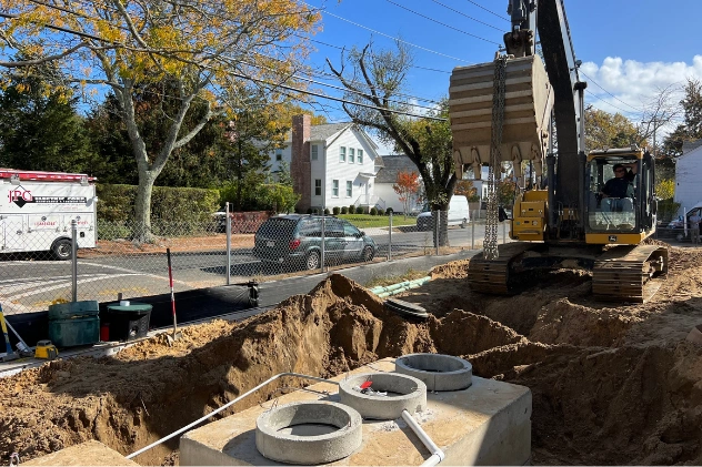 Excavator and workers installing a new septic tank on a property.