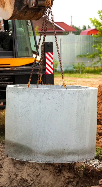 Heavy machinery lifting a septic tank for installation.