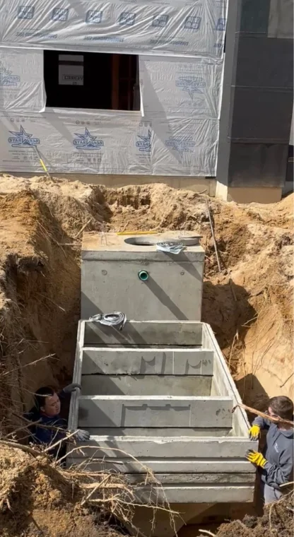 Workers installing a large septic tank in an excavation site.
