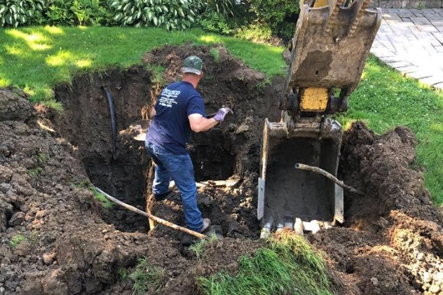 Worker pumping and maintaining a cesspool system with heavy machinery
